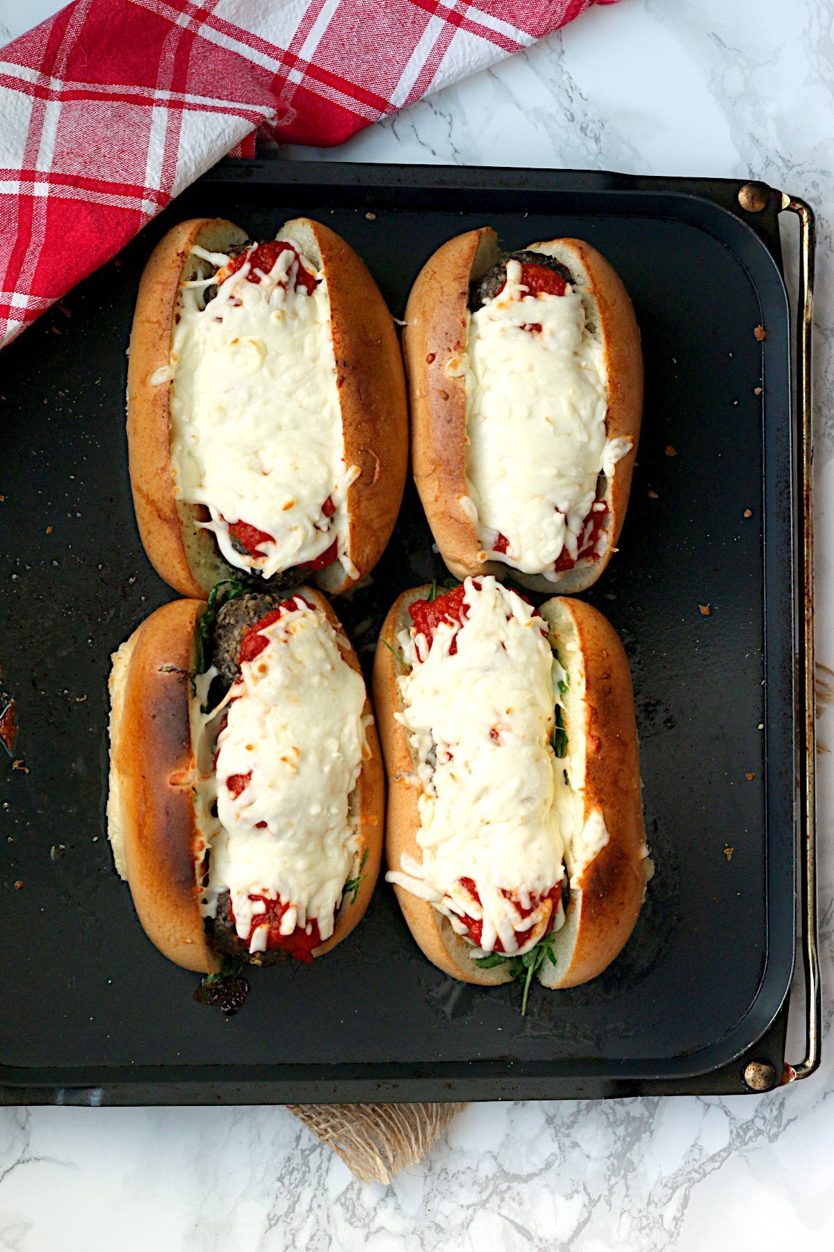 An overhead photo of four Meatball Subs on a baking tray.