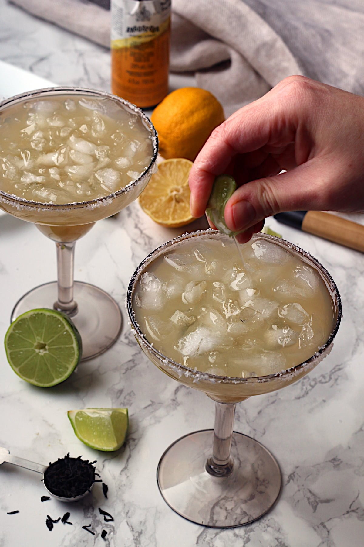 A hand squeezing lime juice into a non-alcoholic lime margarita.