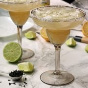 2 non-alcoholic lime margaritas over ice in smoky grey margarita glasses.