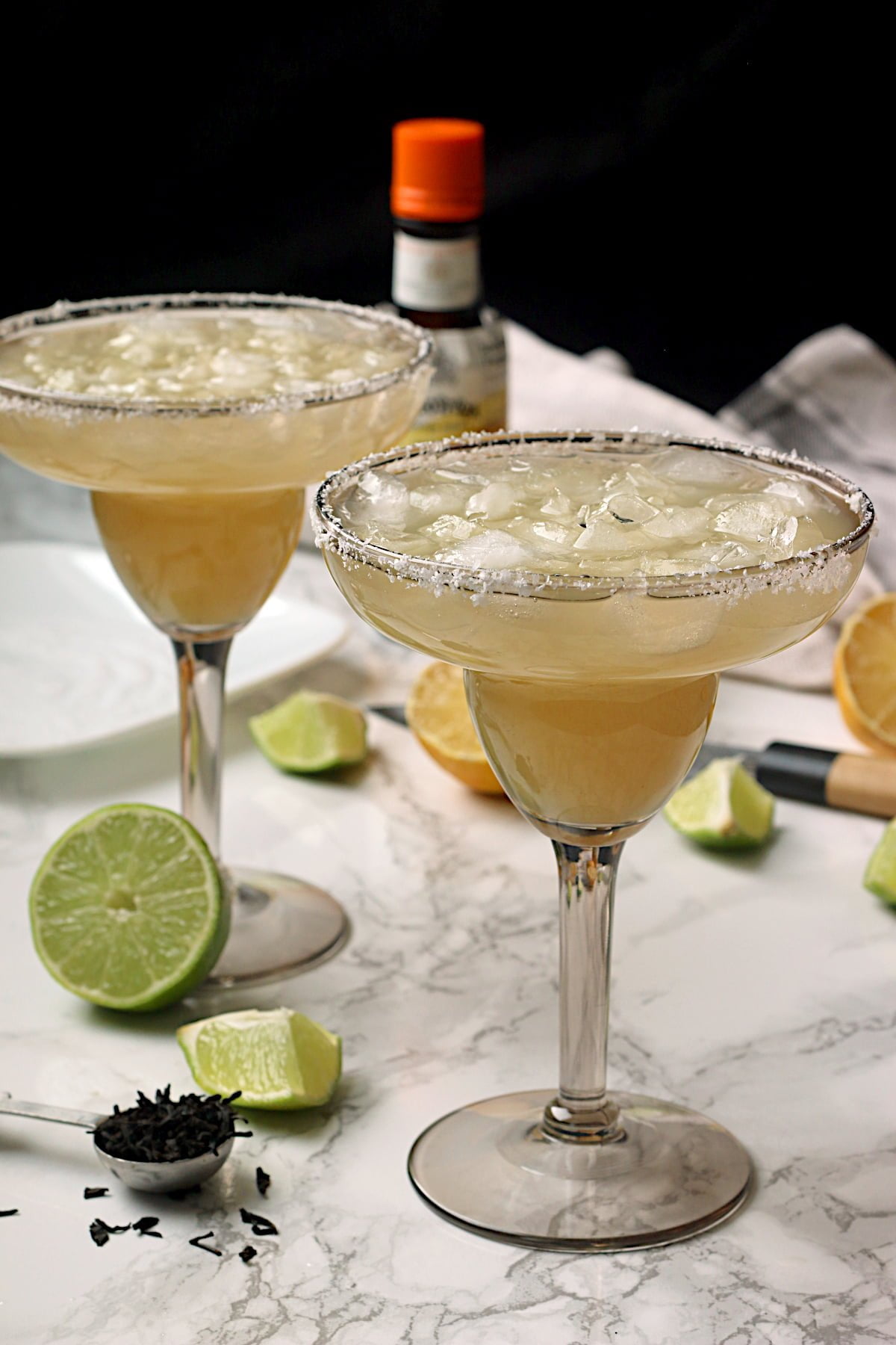 2 non-alcoholic lime margaritas over ice in smoky grey margarita glasses.