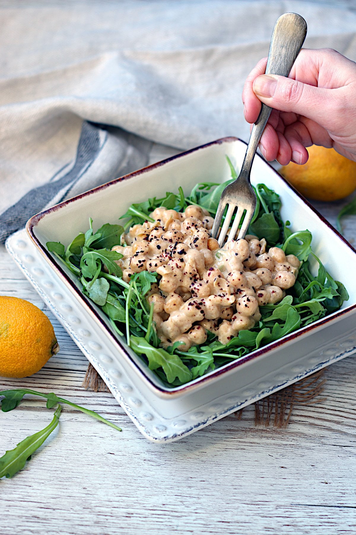 A fork scooping from a bowl of Lazy Chickpea Salad over arugula.
