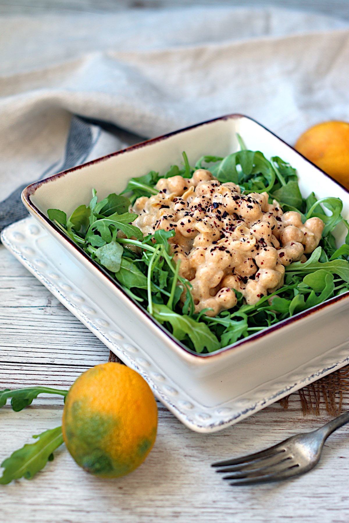 Lazy Chickpea Salad over baby arugula in a square bowl.