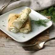 Nalysnyky (Savory Ukrainian Crepes with Dill and Cottage Cheese) on a small, square, white plate.