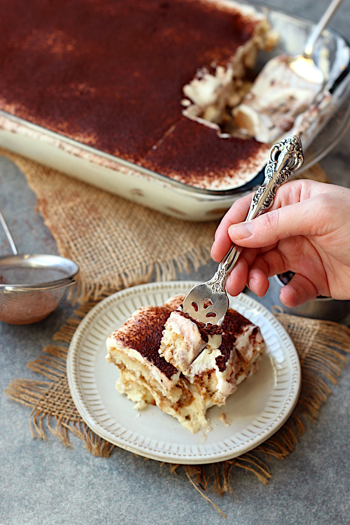 A fork scooping some Cottage Cheese Tiramisu from a small plate.
