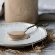 A spoonful of homemade Strawberry Rhubarb Curd on a small, white plate.