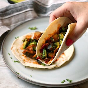 A hand holding a Spicy Zucchini Taco.