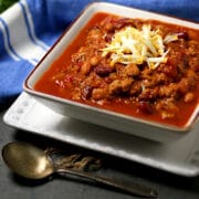 Smoky Chipotle Turkey Chili topped with shredded cheese in a square bowl.