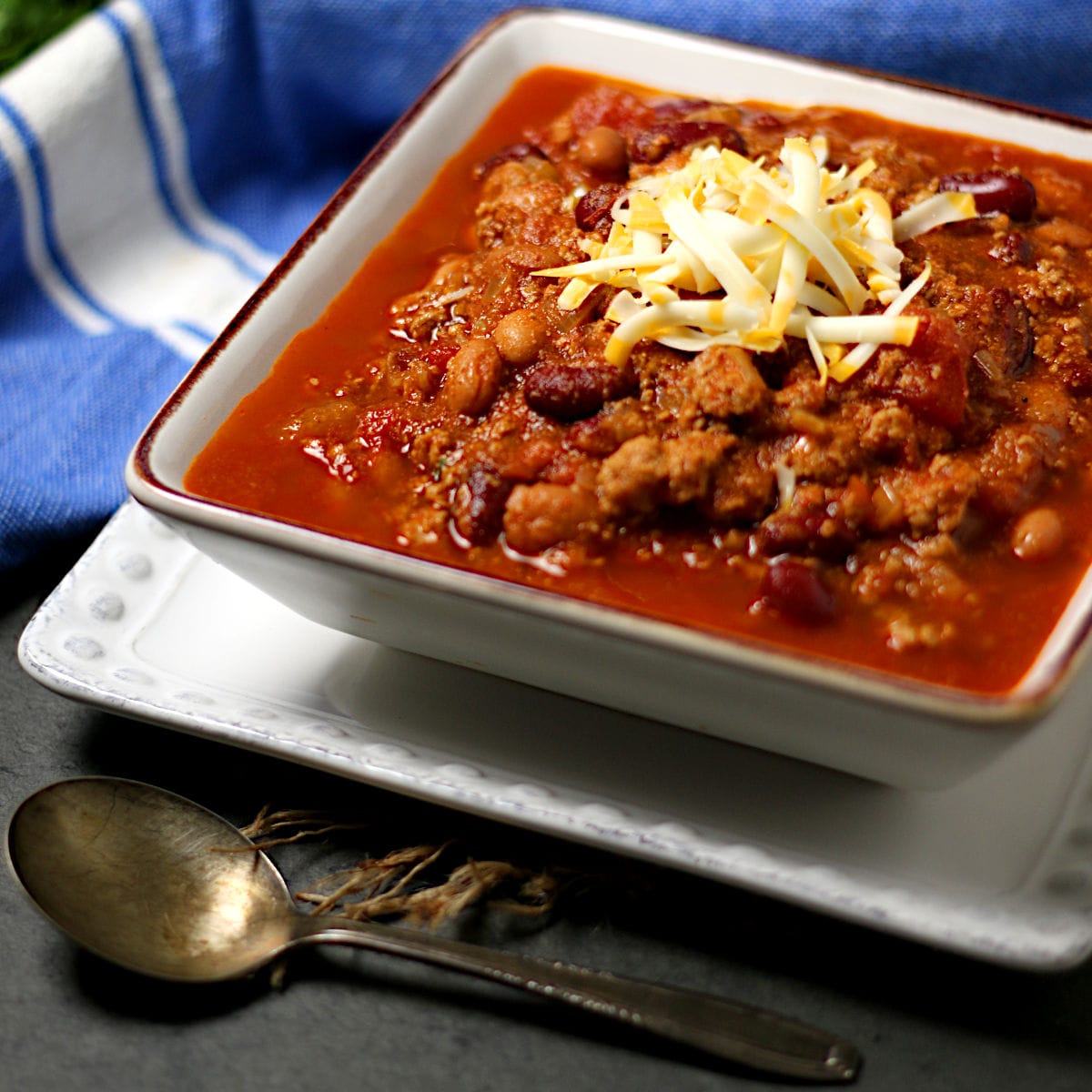 Smoky Chipotle Turkey Chili Smoky Chipotle Turkey Chili topped with shredded cheese in a square bowl.