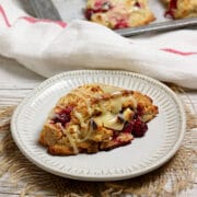 A Cranberry Orange Scone with White Chocolate on a small white plate.