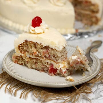 A slice of Homemade Cherry Chip Cake on a small white plate.