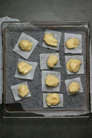 Blobs of choux pastry dough on an air-fryer tray.