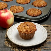 An apple cinnamon oatmeal muffin on a small white plate.