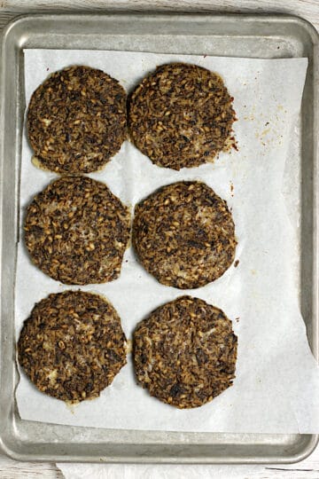 Mushroom Grain Burger patties on a parchment-lined baking sheet after baking.
