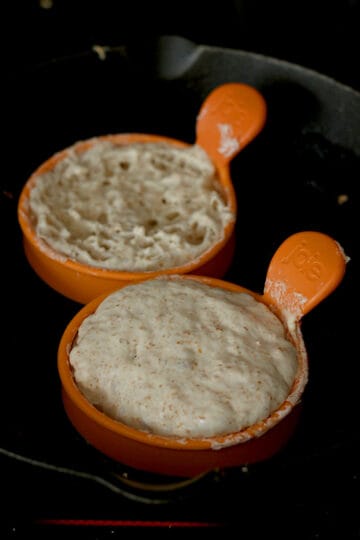Cooking crumpets in silicone egg rings in a cast iron pan.
