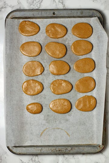 Peanut butter candy filling cut into egg shapes on a parchment-lined baking sheet.