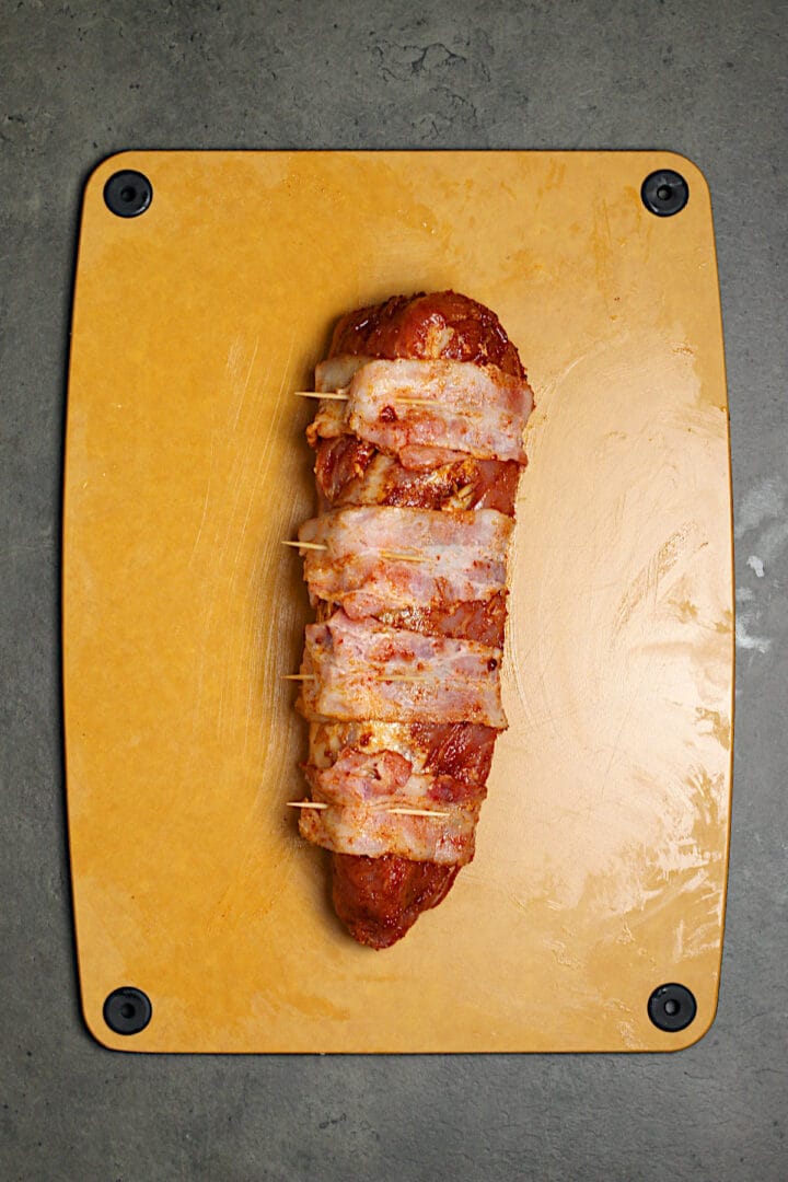 A pork tenderloin that has bee rubbed with a smoked paprika seasoning mixture and wrapped with 4 slices of bacon.