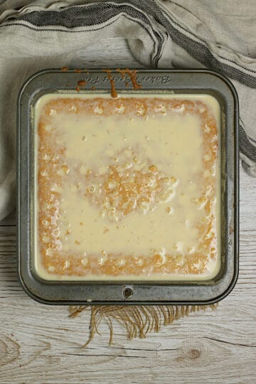 Overhead photo of a gluten-free corn tres leches cake immediately after pouring on the milk soak.