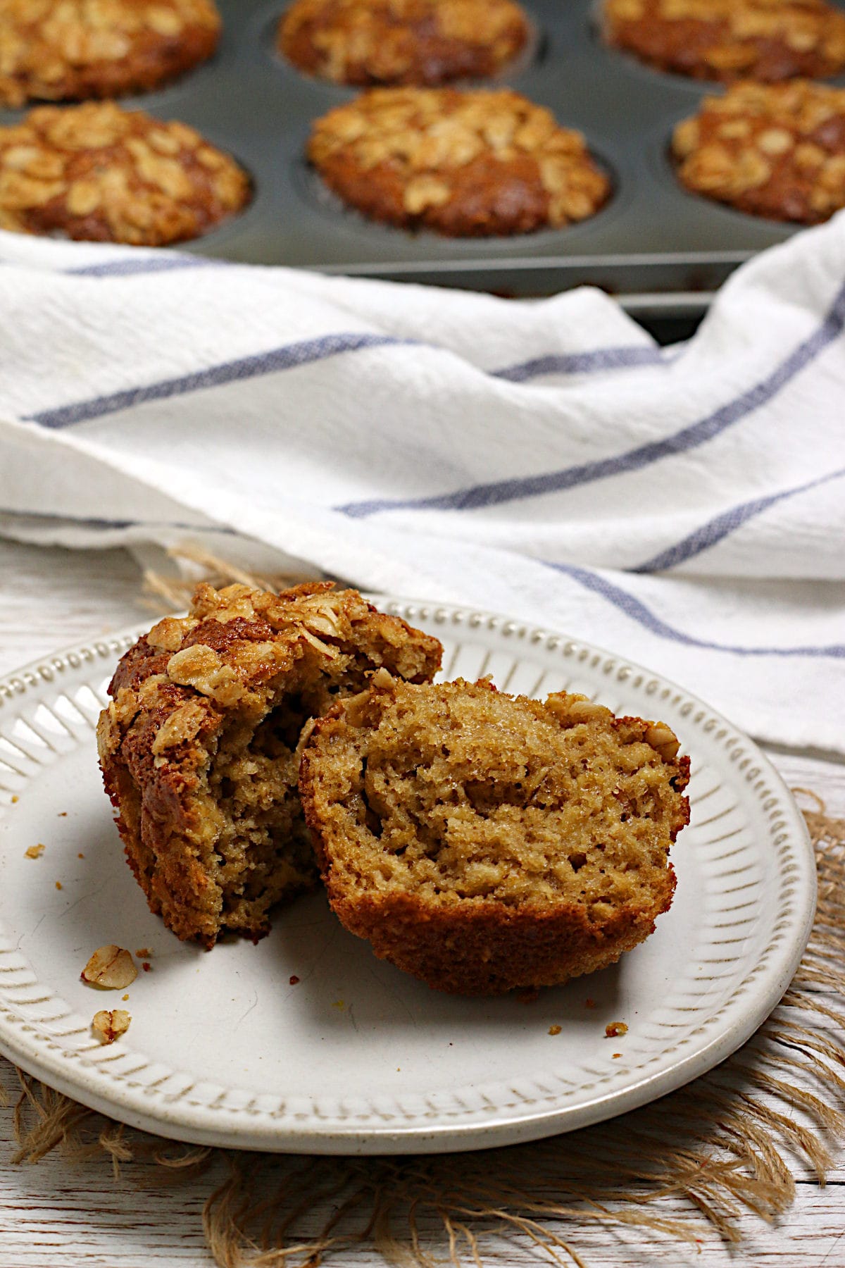 Maple and Brown Sugar Oatmeal Muffins A homemade Maple and Brown Sugar Oatmeal Muffin broken in half on a small white plate.
