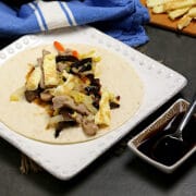 Easy Weeknight Moo Shu Pork in a flour tortilla on a square, white plate.