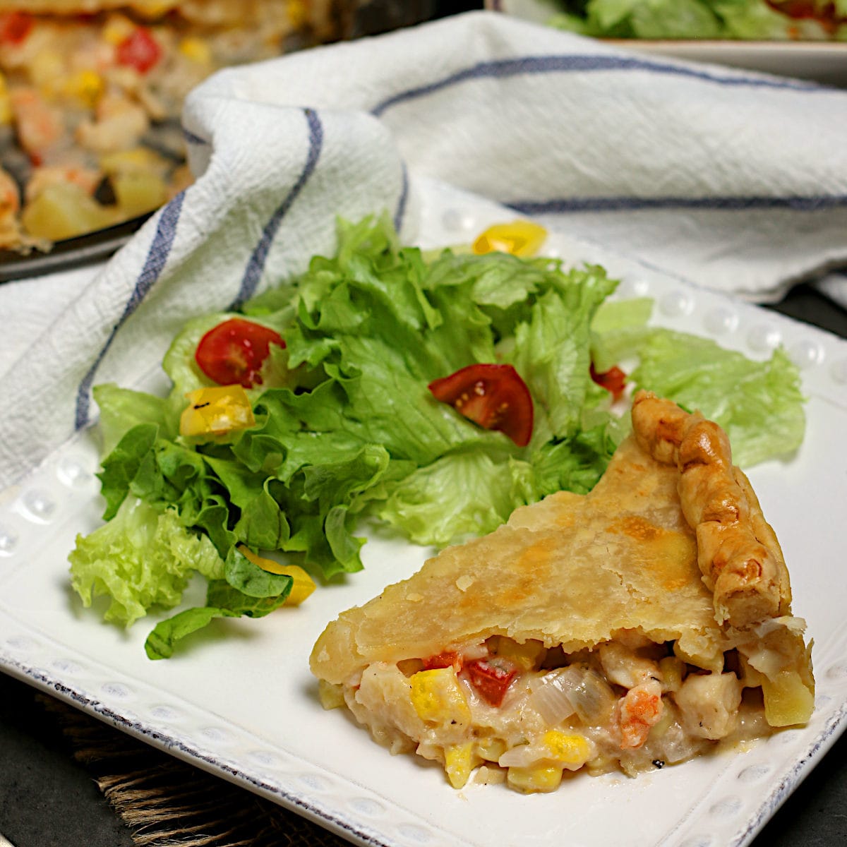 Seafood Pie A slice of seafood pie and a side salad on a white square plate.