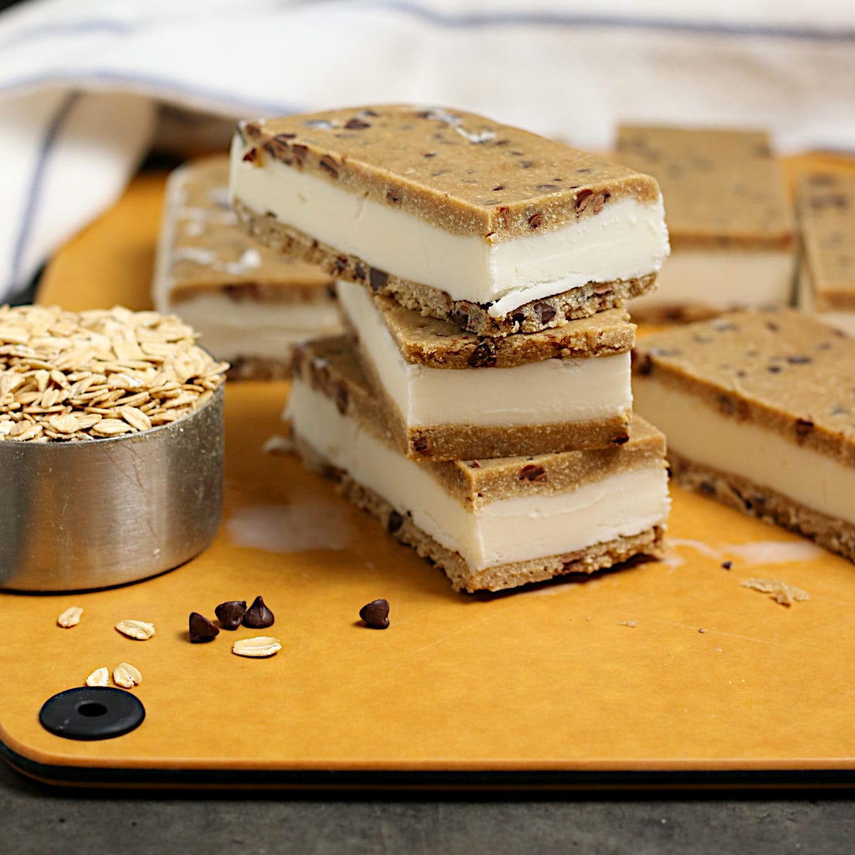Oatmeal Chocolate Chip Cookie Dough Ice Cream Sandwiches A stack of Oatmeal Chocolate Chip Cookie Dough Ice Cream Sandwiches on a cutting board.