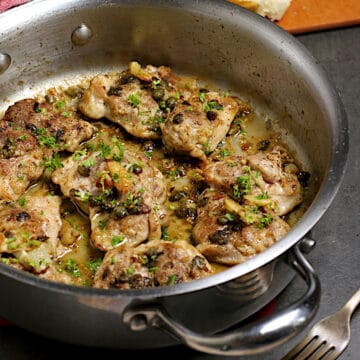 Chicken thighs with anchovies and capers in a saute pan.