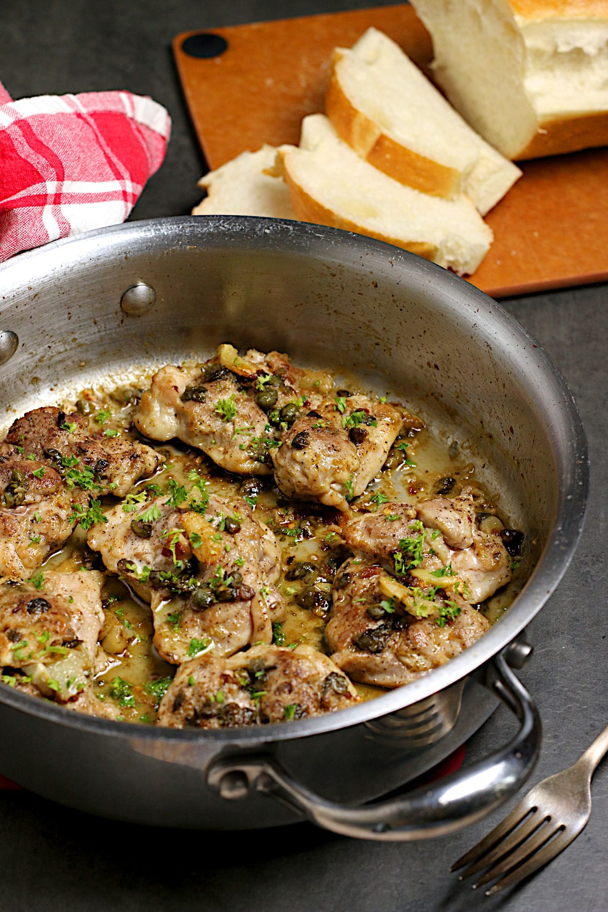 Chicken thighs with anchovies and capers in a saute pan.