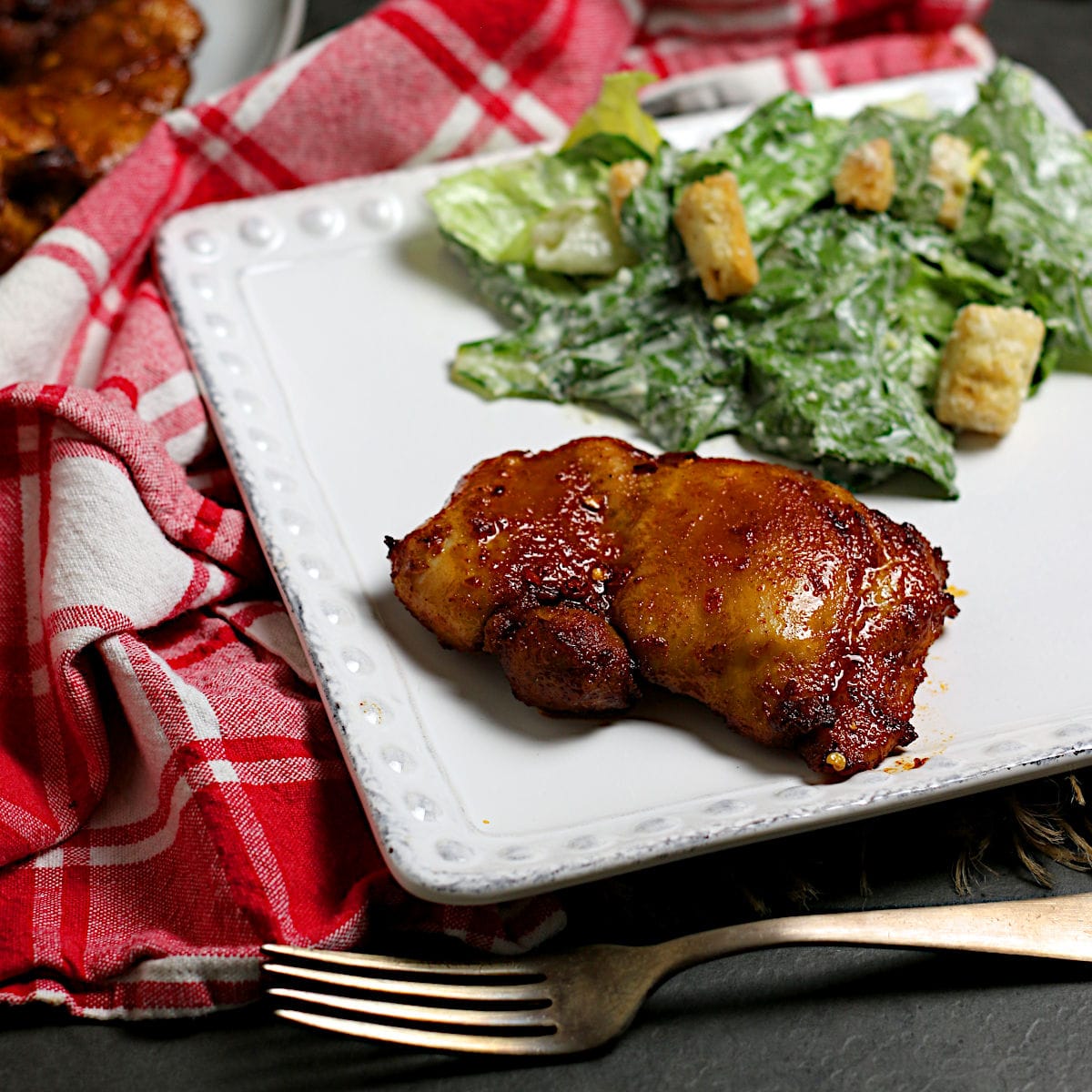 A Hot Honey Glazed Chicken Thigh on a white plate.