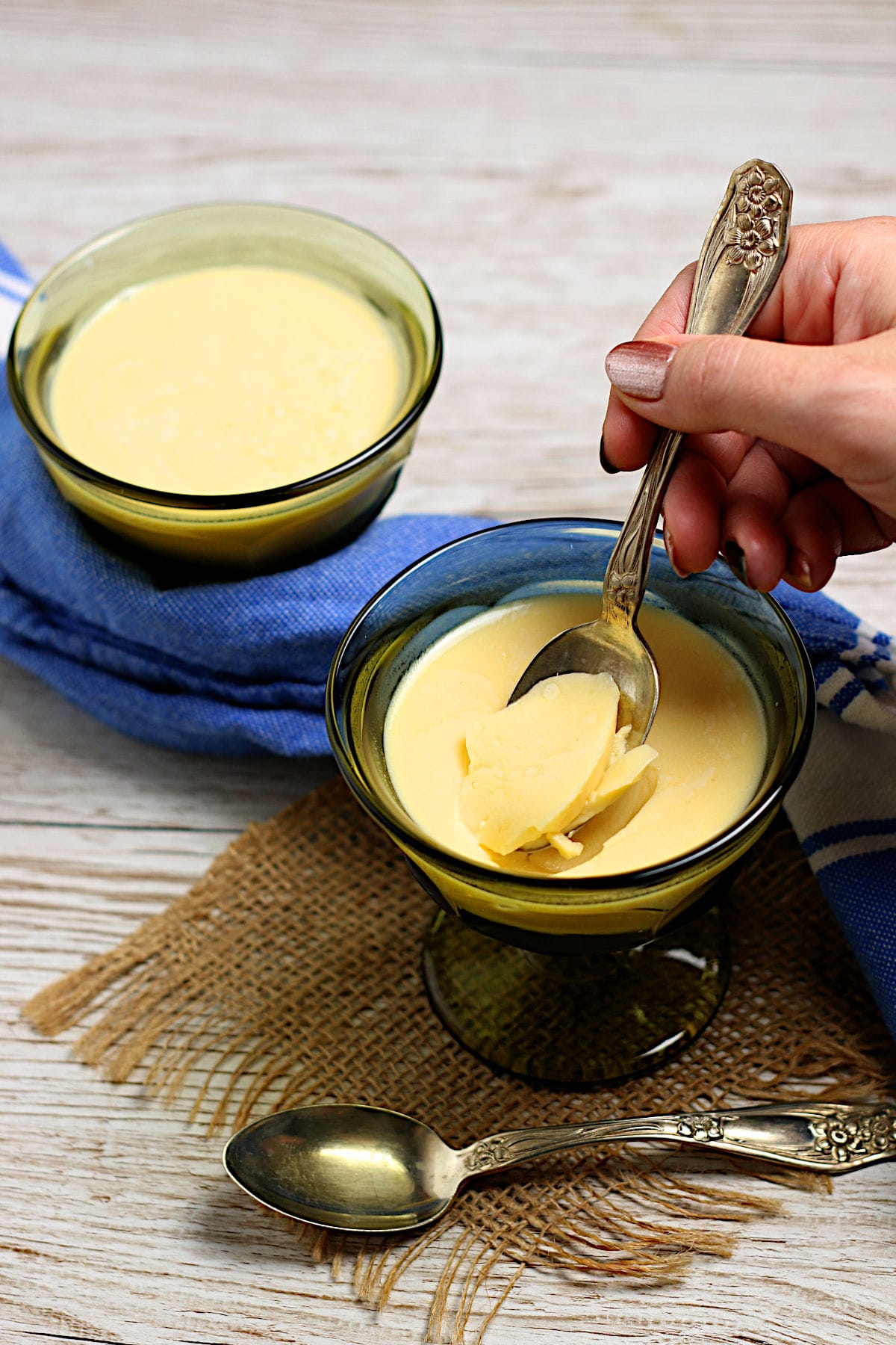 A hand scooping some mango pudding from a small green dish.