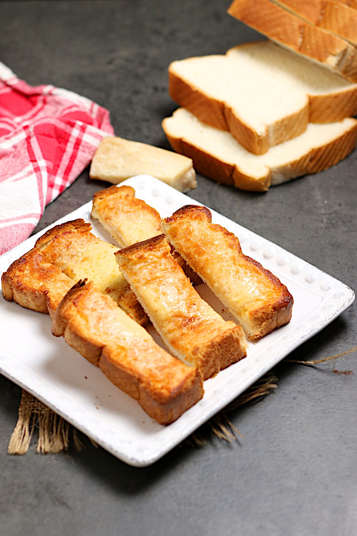 Three Cheese Toast fingers on a white plate.