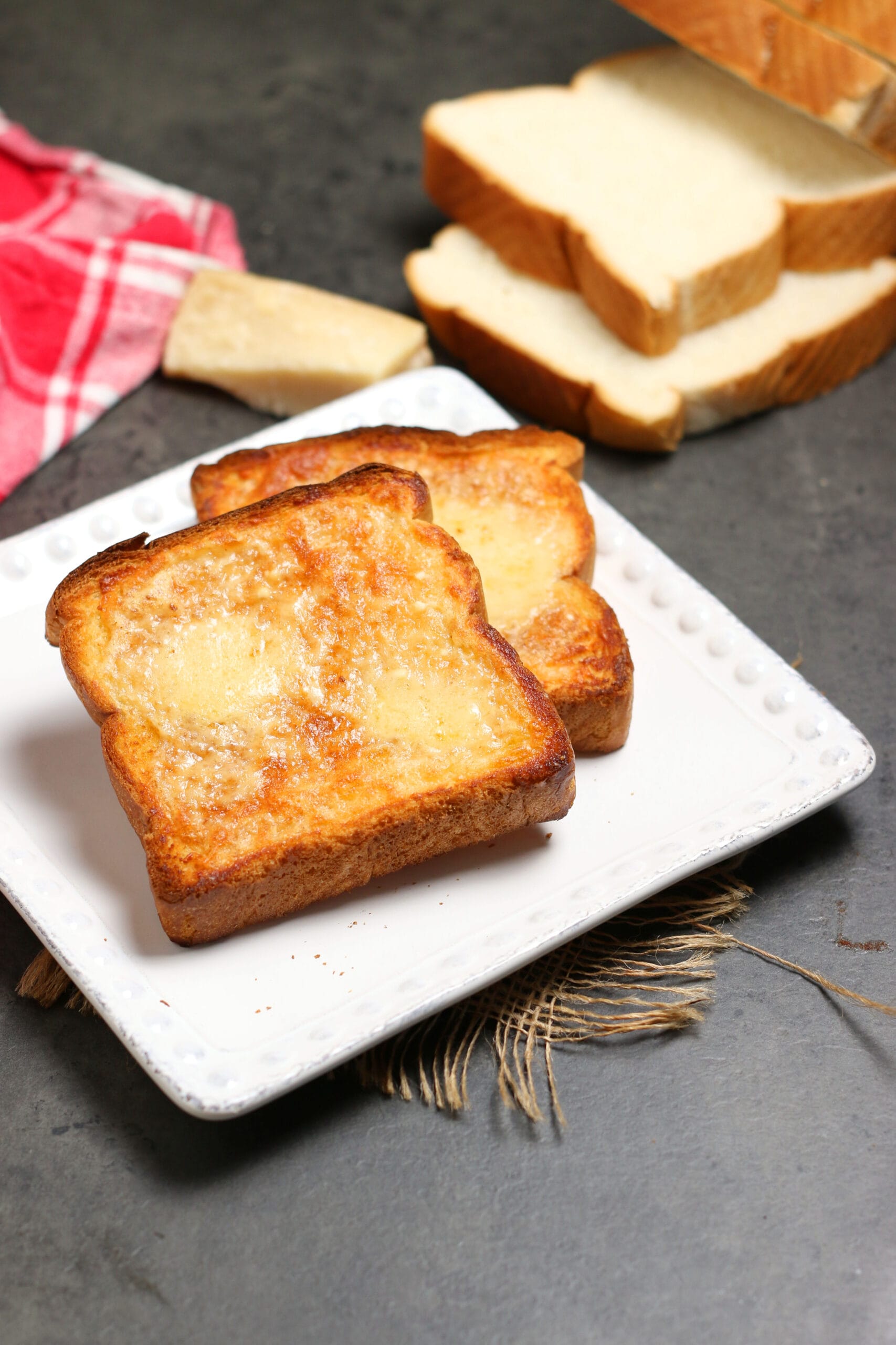 Two slices of Three Cheese Toast on a white plate.