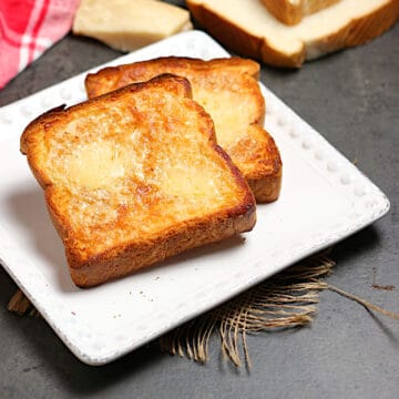 Two slices of Three Cheese Toast on a white plate.