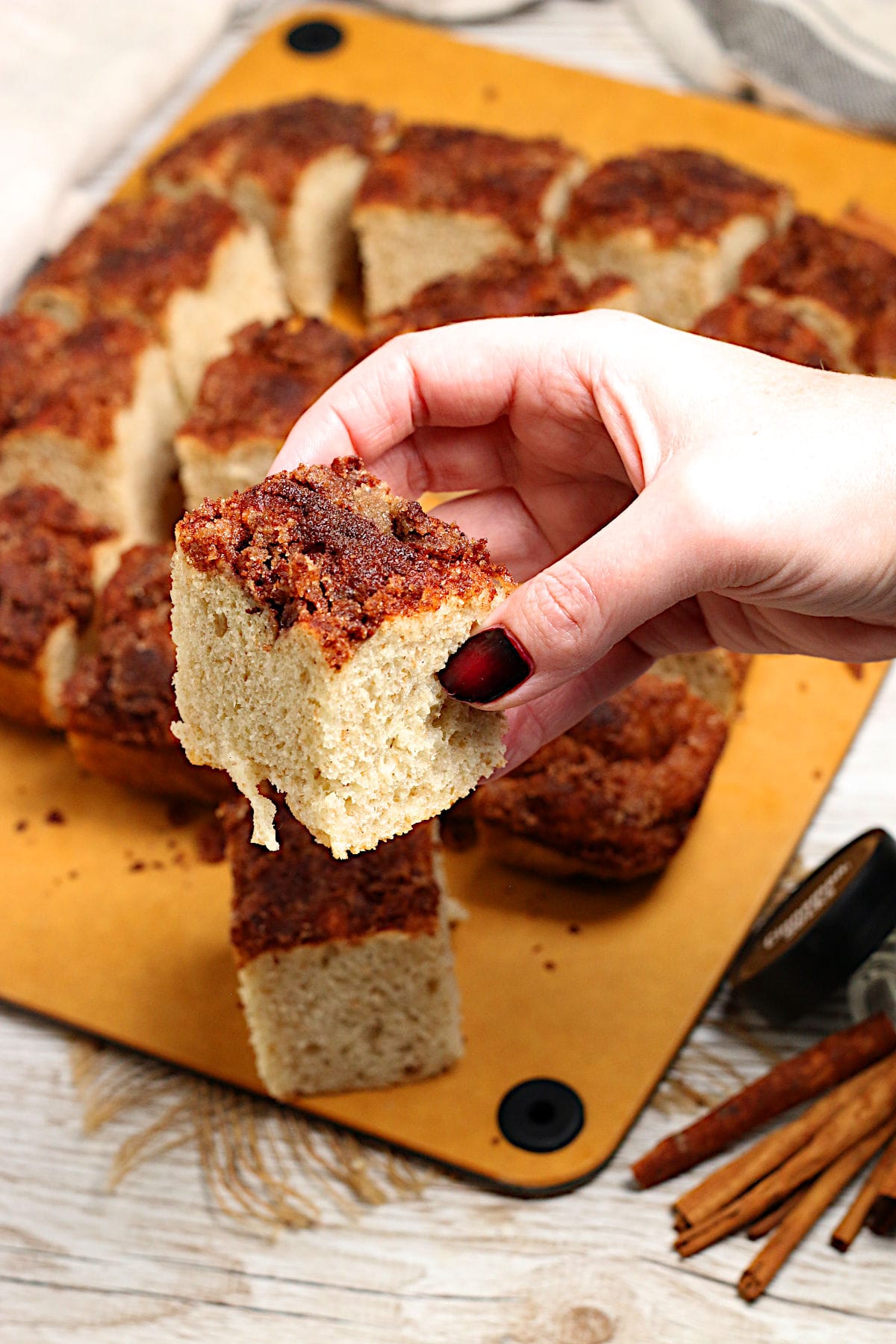 Cinnamon Toast Focaccia A hand holding a piece of Cinnamon Toast Focaccia.