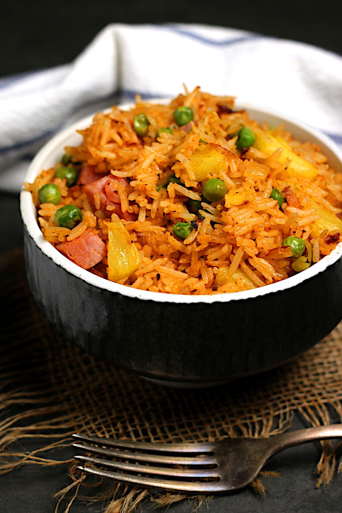 A closeup photo of Ham and Pineapple Fried rice in a black bowl.