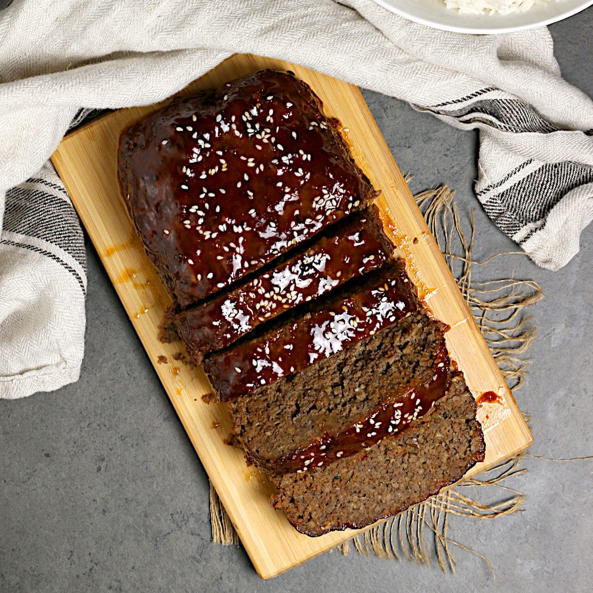 Overhead photo of Sliced Korean Beef and Mushroom Meatloaf with Gochujang glaze on a bamboo cutting board.