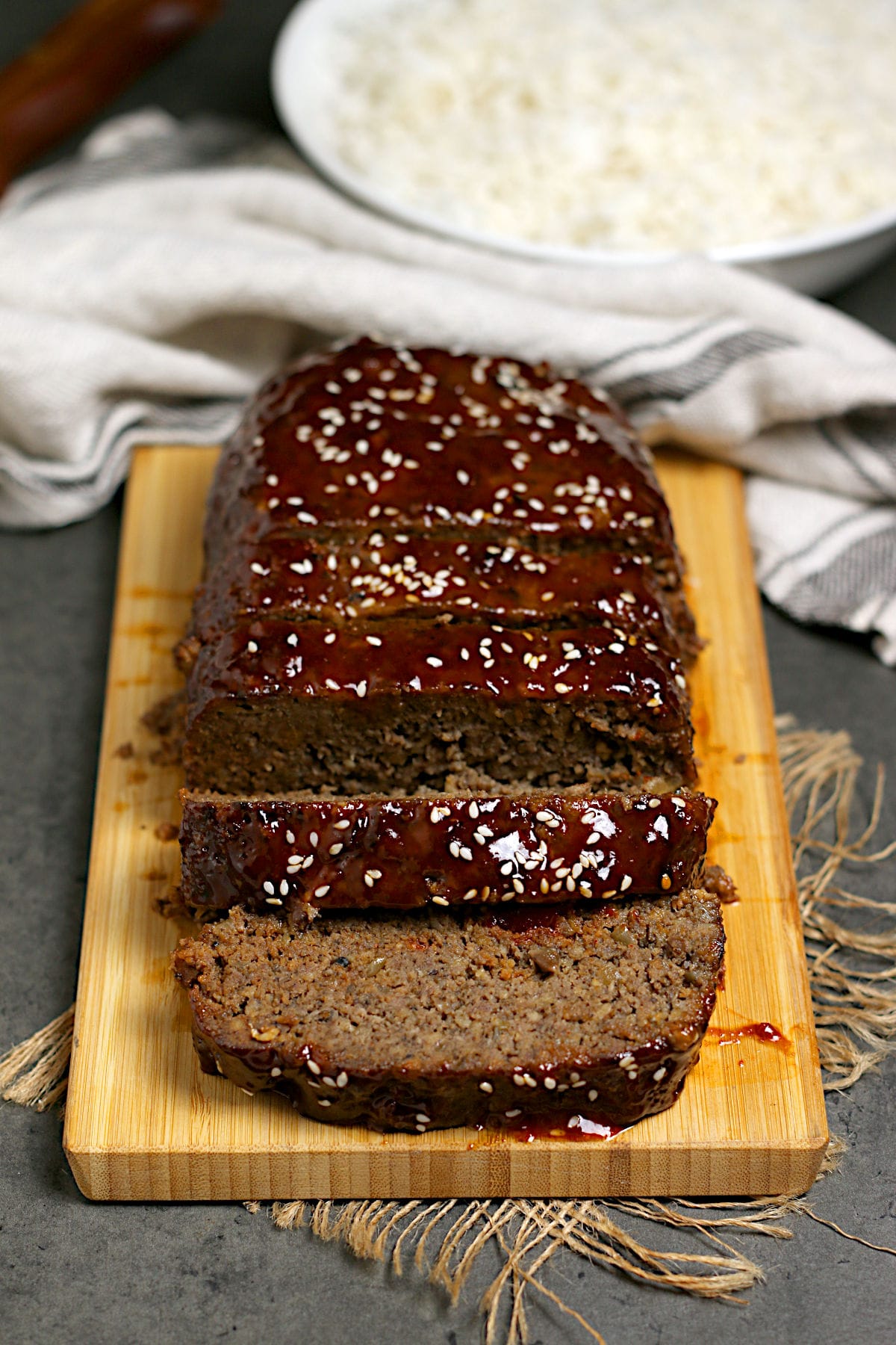 Sliced Korean Beef and Mushroom Meatloaf with Gochujang glaze on a bamboo cutting board.