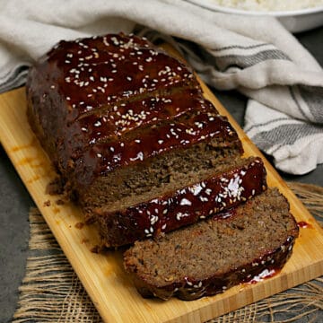 Sliced Korean Beef and Mushroom Meatloaf with Gochujang glaze on a bamboo cutting board.