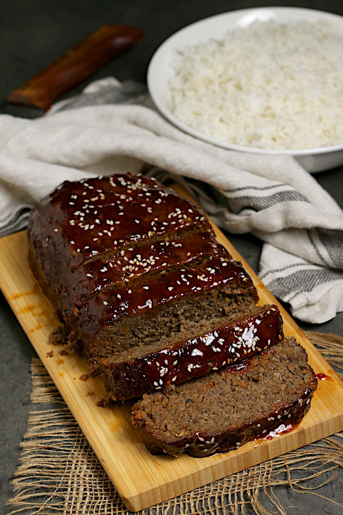 Sliced Korean Beef and Mushroom Meatloaf with Gochujang glaze on a bamboo cutting board.