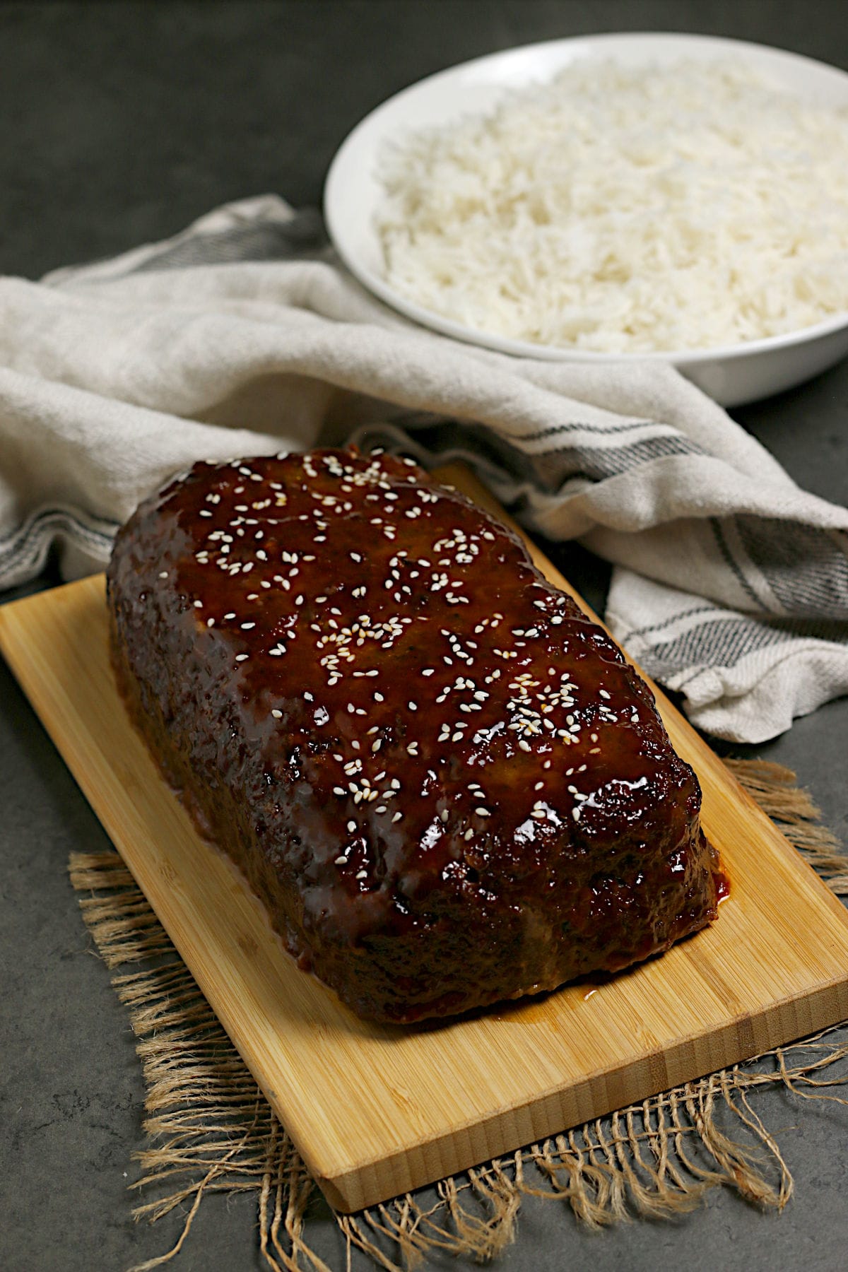 Whole Korean Beef and Mushroom Meatloaf with Gochujang glaze on a bamboo cutting board.