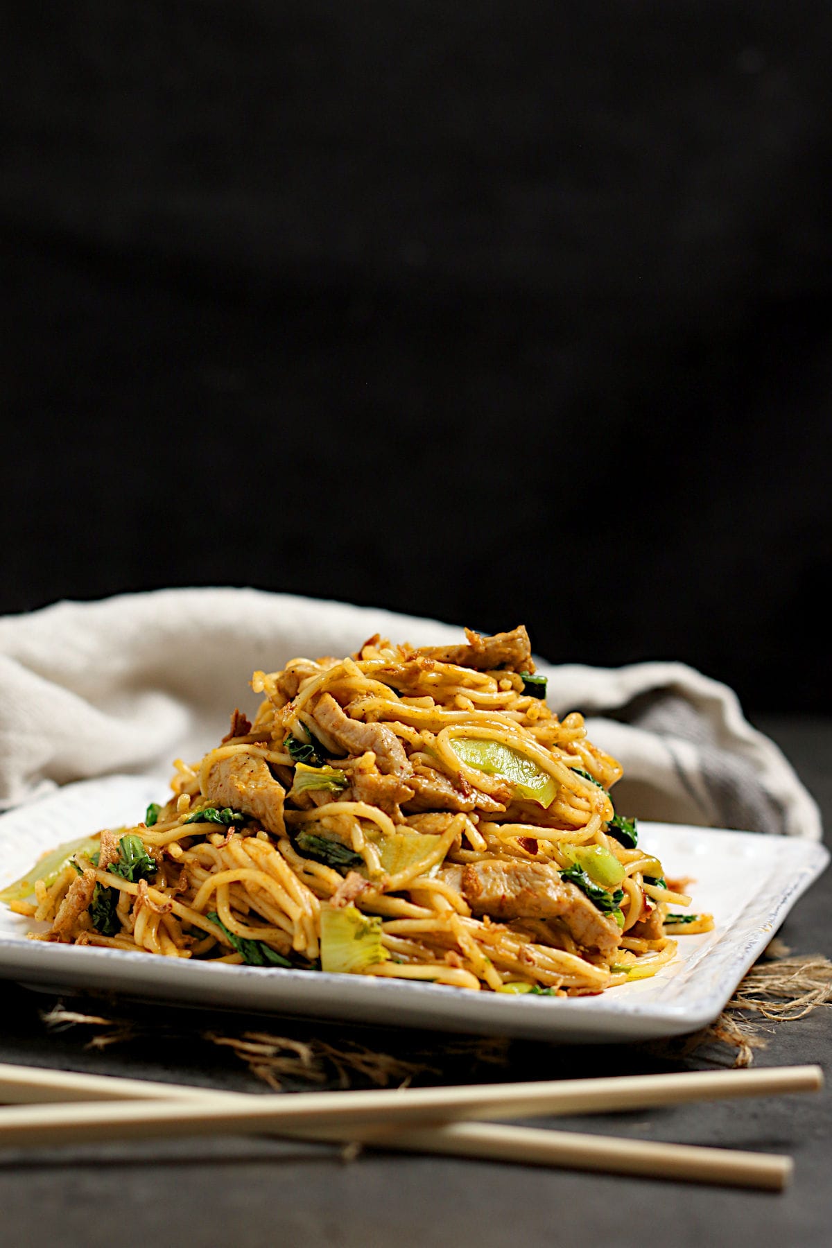 Spicy Noodles with Pork and Bok Choy on a square, white plate.