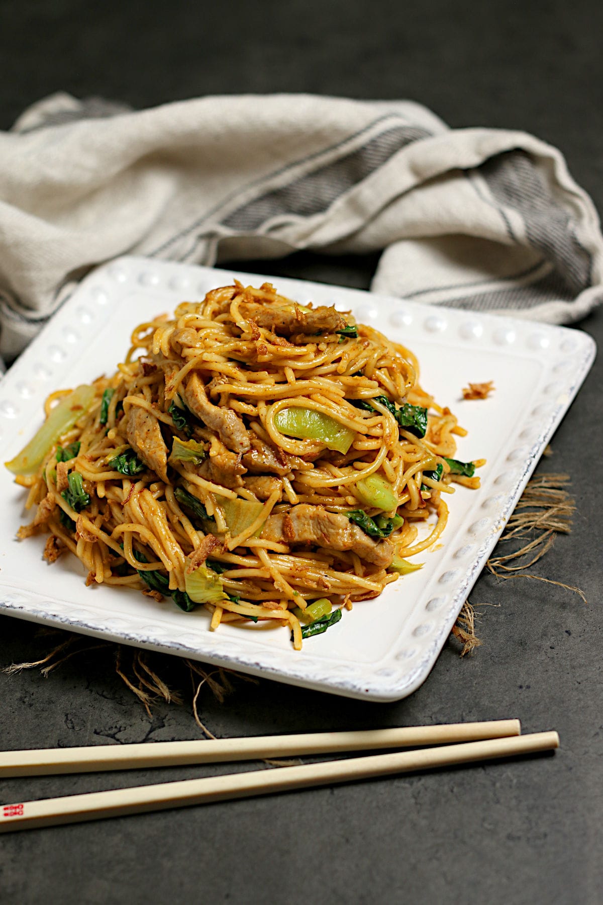 Spicy Noodles with Pork and Bok Choy on a square, white plate.