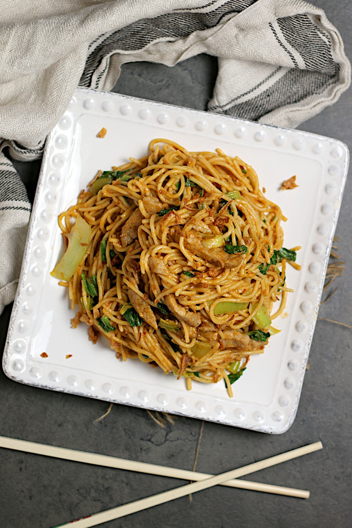 An overhead photo of Spicy Noodles with Pork and Bok Choy on a square, white plate.