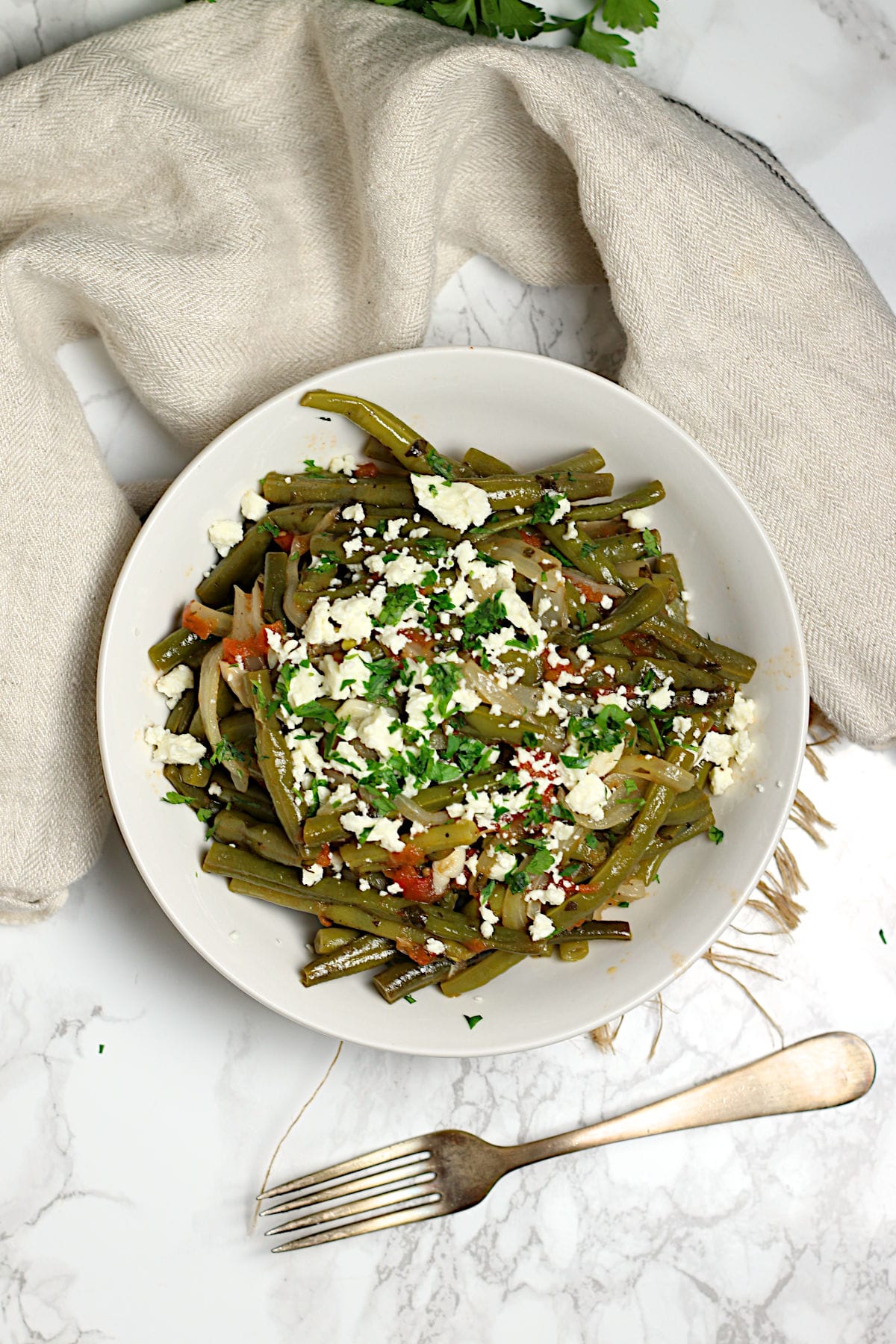 An overhead photo of Greek-Style Green Beans in a white bowl.