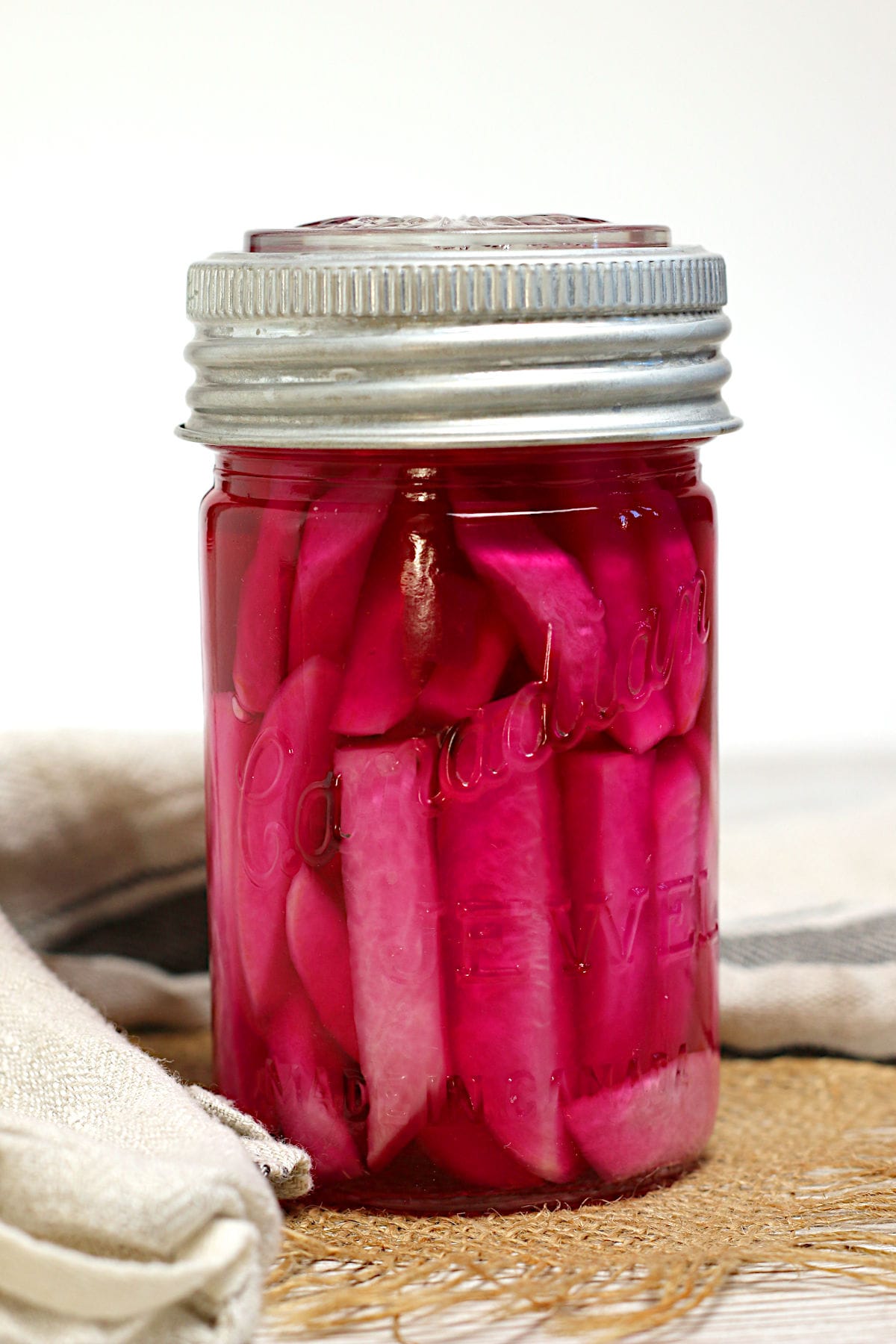 Closeup photo of pink pickled turnips in a jar.