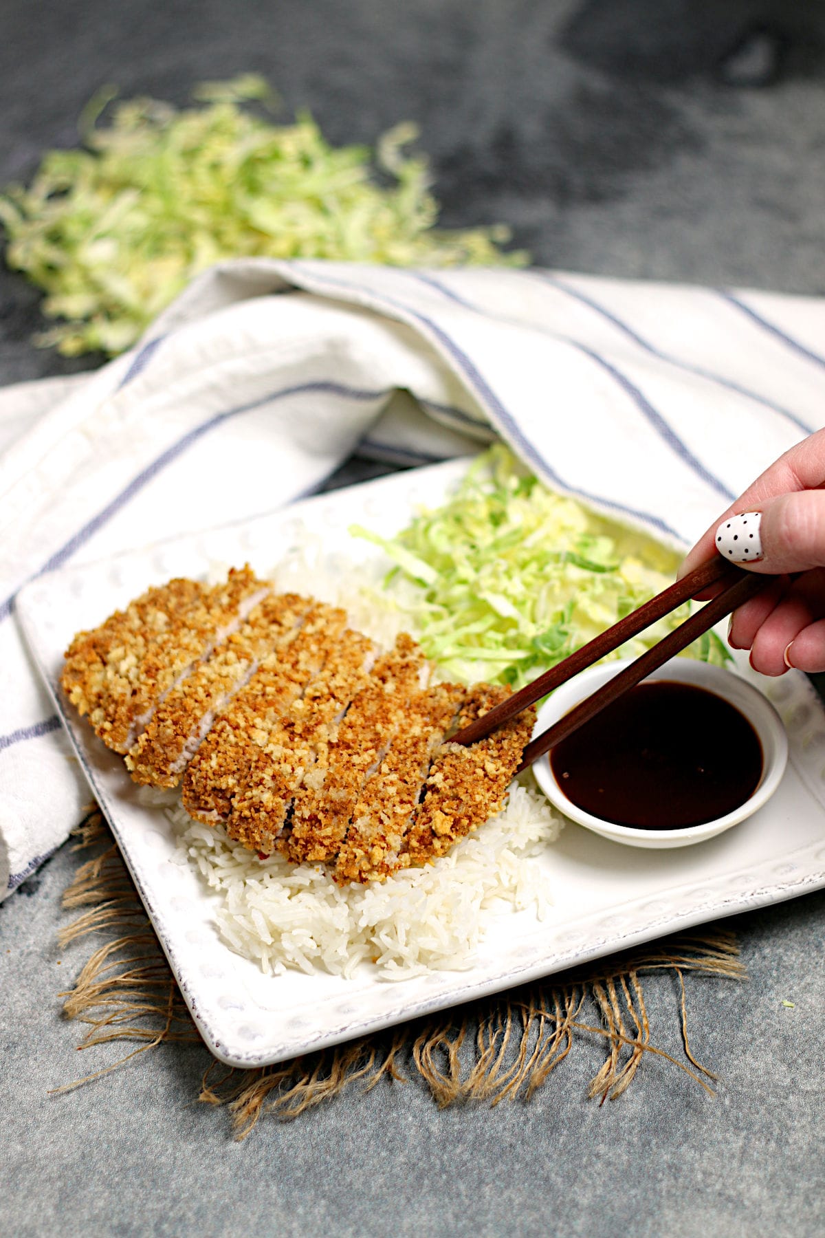 A hand grabbing a slice of Air-Fryer Tonkatsu with chopsticks.
