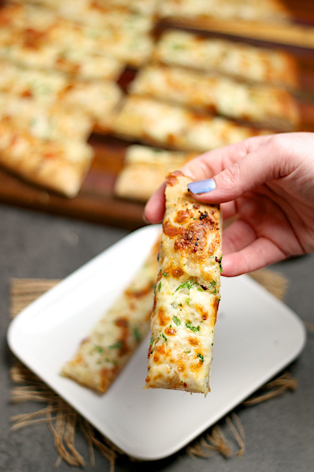 A hand holding a piece of Nova Scotia Garlic Fingers.