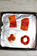 Roasted red bell pepper on a small foil-lined baking pan.