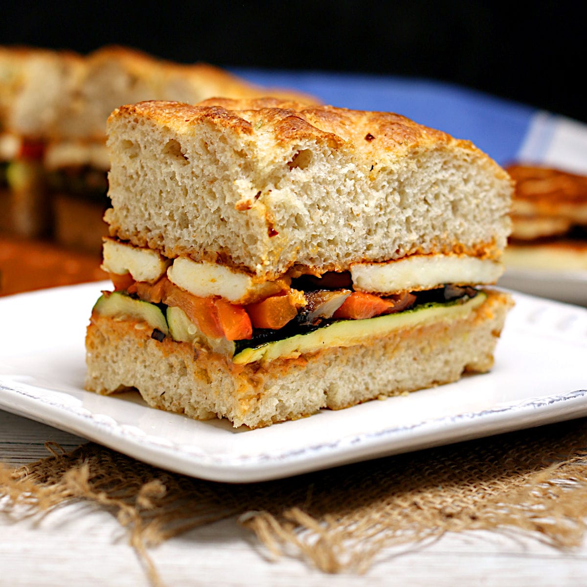 A Roasted Vegetable and Halloumi Sandwich on a white plate.
