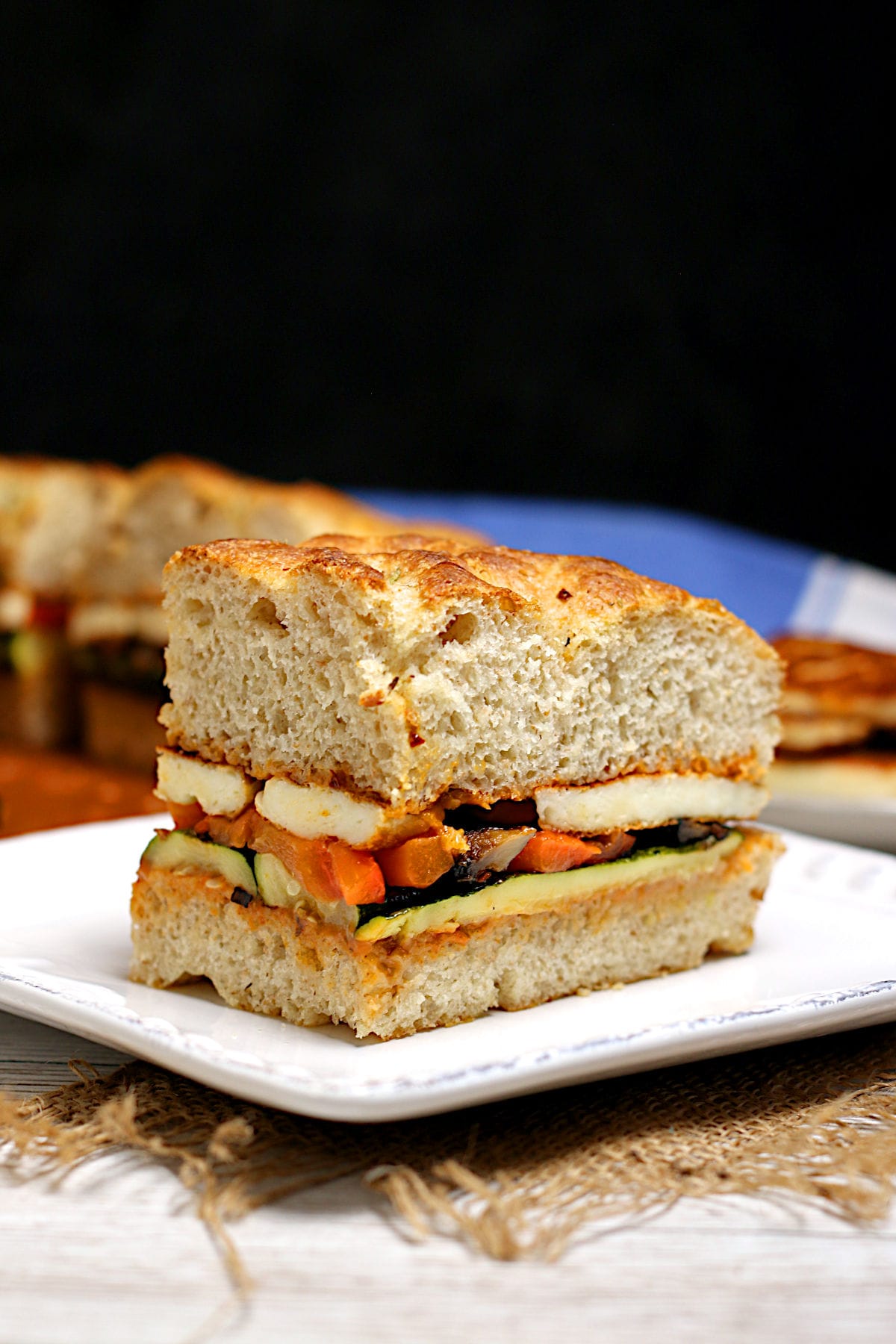 A Roasted Vegetable and Halloumi Sandwich on a white plate.