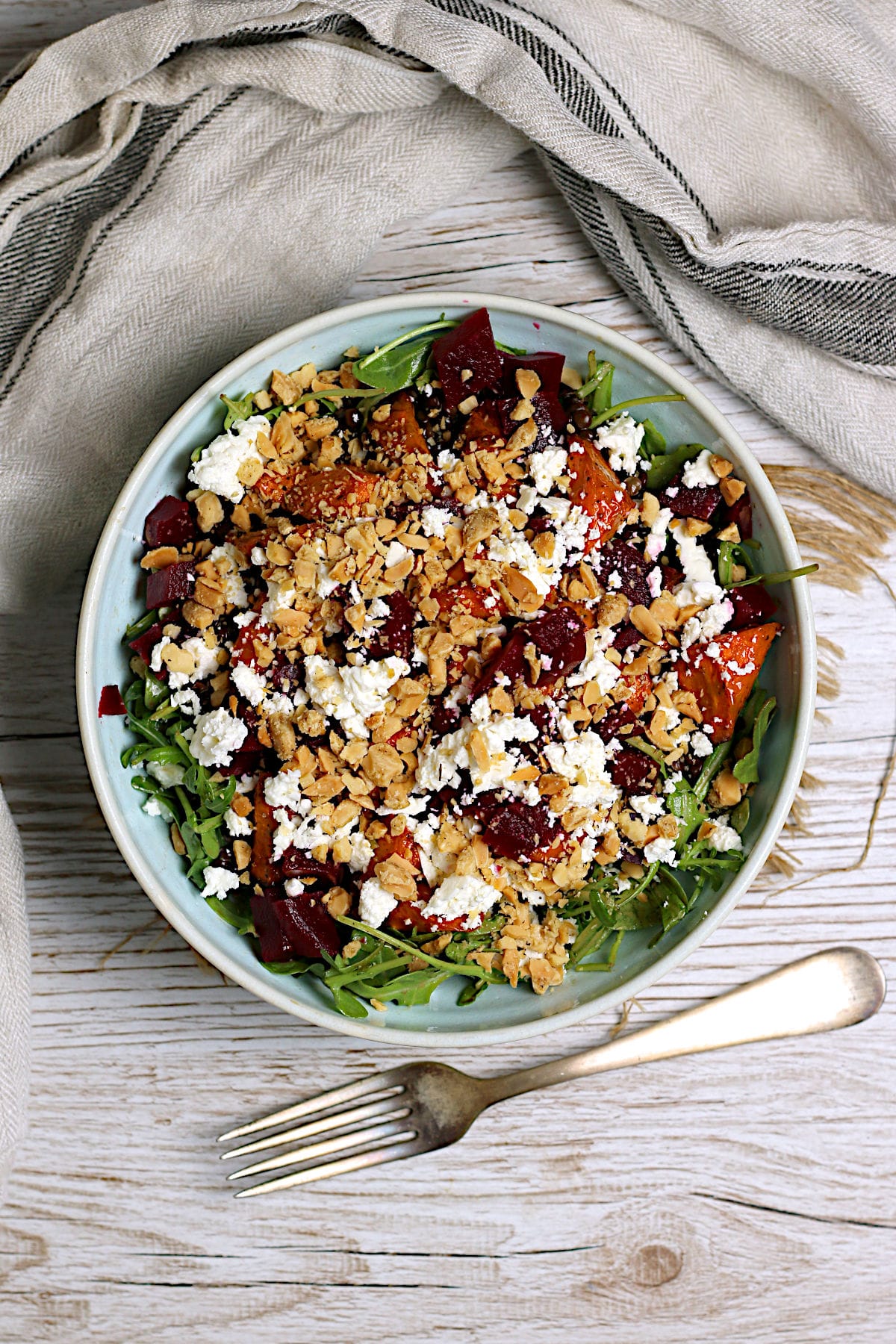 Overhead photo of Arugula Salad with Root Vegetables and Lentils in a pale blue bowl.